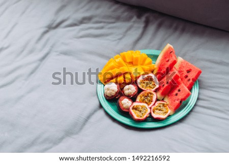 Plate with tropical fruit in grey bed, breakfast