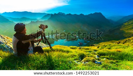 photographer man taking photos in nature mountain landscape. Fagaras, Romania