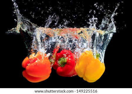 Red, orange and yellow peppers splashing water