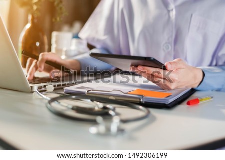 Female doctor working on desk with laptop computer and paperwork in the office. Medical and doctor concept.