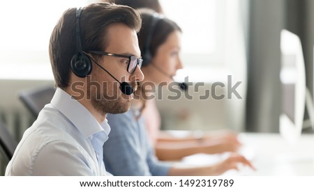 Confident call center operator agent in headset with microphone consulting client online close up, busy employee working in customer support service office, coworking space, horizontal photo Royalty-Free Stock Photo #1492319789