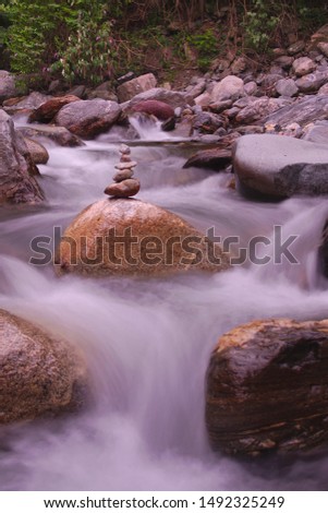 Stone Tower - Stone Pyramid in front of a waterfall of a river in the mountains of Austria - time exposure