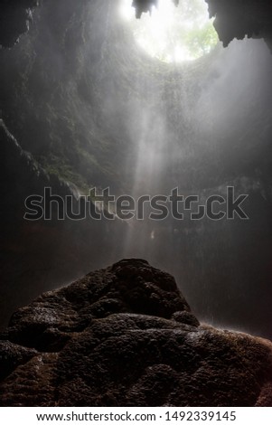 Light rays hitting limestone inside dark deep cave called Jomblang cave which is 60m deep an iconic adventure spot in Indonesia