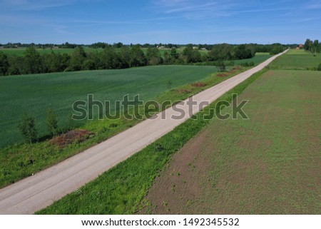 Aerial view of gravel road on farmland fields in spring time