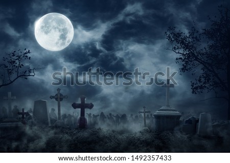 Zombie Rising Out Of A Graveyard cemetery In Spooky dark Night full moon. Holiday event halloween background concept. Royalty-Free Stock Photo #1492357433