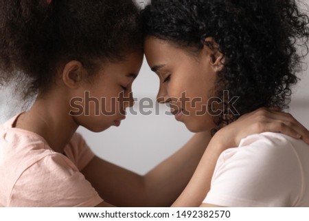 Side view close up faces of african mother and daughter touches foreheads moment of tenderness and caress. Concept of ask forgiveness or show gratitude for adoption to new mom, family is love concept Royalty-Free Stock Photo #1492382570