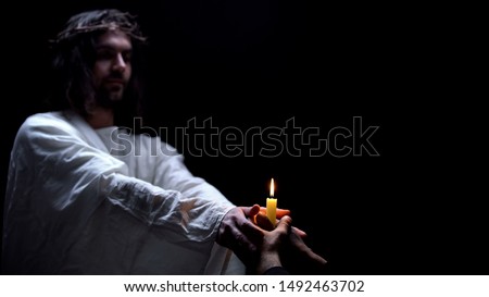 Savior supporting religious man holding candle, spiritual ritual, God kindness