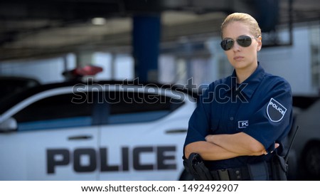 Serious policewoman putting on sunglasses and posing on camera, public safety Royalty-Free Stock Photo #1492492907