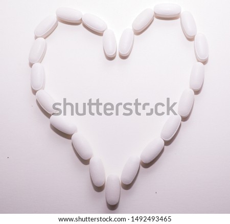 White oval pills heart shaped as a background for pharmacy concept.