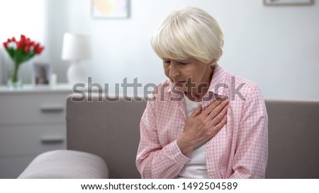 Old woman with heart disease holding hand on chest, suffering from tachycardia Royalty-Free Stock Photo #1492504589