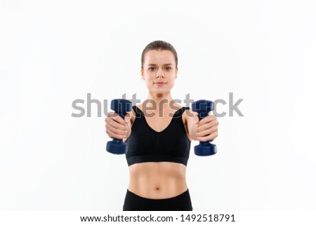 Young sporty blond woman in a black sportswear exercising with hand weights isolated over white background. Muscle-building exercises.