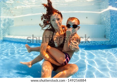 Mother and son having fun underwater in swimming pool.