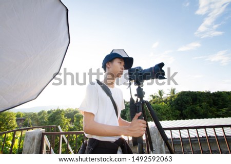 Young photographer using digital camera and set a outdoor studio light to prepare shooting a model or product at customer place