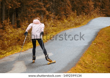 Woman cross-country skiing with roller ski in park