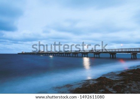 Wood pier in ocean in Miami Beach in evening with long expose