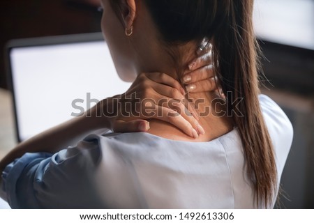 Tired woman massaging rubbing stiff sore neck tensed muscles fatigued from computer work in incorrect posture feeling hurt joint shoulder back pain ache, fibromyalgia concept, close up rear view Royalty-Free Stock Photo #1492613306