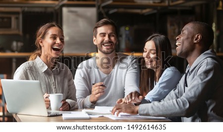Happy diverse friends team studying together talk laugh prepare for exam sit at cafe table, cheerful multicultural young students people group help do creative research project having fun in campus Royalty-Free Stock Photo #1492614635