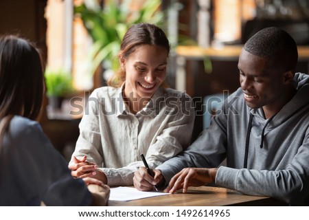Happy mixed ethnicity couple customers sign mortgage loan contract, smiling interracial husband and wife make insurance investment deal put signature on paper meeting broker bank agent insurer