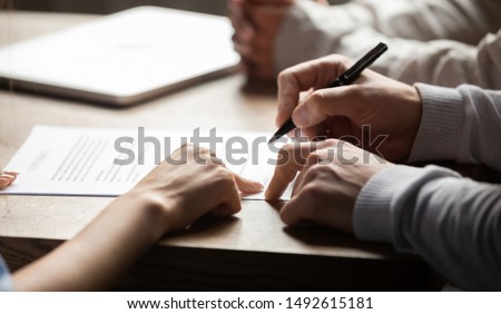 Solicitor pointing at insurance contract showing male client where to write signature sign sale purchase employment agreement at meeting make financial business deal, bank loan service, close up view Royalty-Free Stock Photo #1492615181