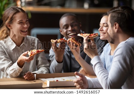 Cheerful multiracial happy best friends couples laugh at funny joke eating pizza in cafe together, happy multicultural young mates having fun sharing food at party meeting in pizzeria sit at table Royalty-Free Stock Photo #1492616057