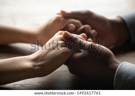 Mixed ethnicity family couple holding hands on table, black man friend husband support woman wife expressing love feelings, trust care honesty in interracial relationship concept, close up view Royalty-Free Stock Photo #1492617761