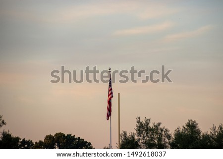 American flag next to one side of football goal post seen at sunset at the end of summer and beginning of football season