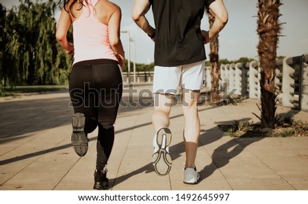 Couple of Caucasian men and Latina women run. Photographic shot from the back