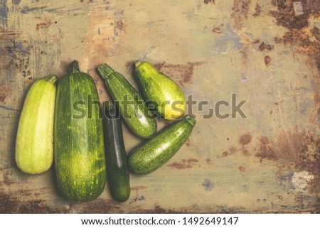 Fresh organic zucchini or green courgette on old metal surface. Top view with copy space. Vintage style. Toned photo