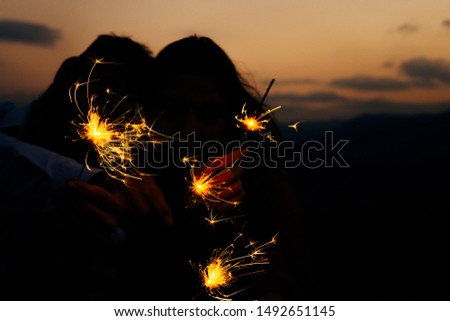 Portrait of young attractive celebrating couple holding firecrackers