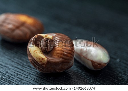 Belgian chocolates on a black wooden background. Photographed close-up.