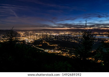 Evening top view of city lights, French Annemasse, Swiss Geneva,lake Geneva and picturesque sky with dark clouds after sunset,photo with long exposure.Department of Haute-Savoie in France.