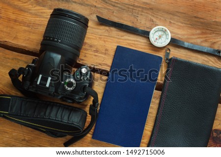 Travel flatlay on brown wooden background with camera, international passports, wallet and compass. Top view of traveler items, lifestyle accessories. Vacation concept.