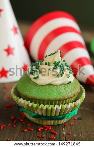 Green birthday cupcake with hats in background