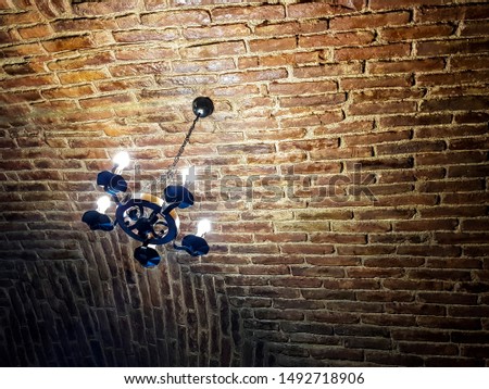 Antique chandelier style with modern lights. It hangs on a red brick ceiling. Rusty look picture.
