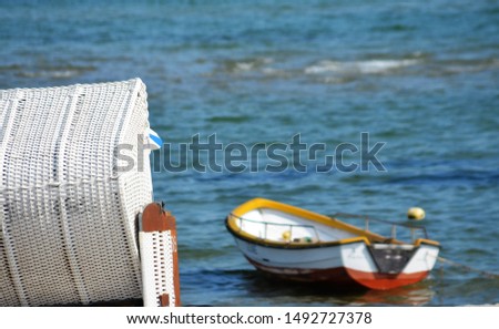 white beach chair and a view of the sea with a small boat. The picture gives peace and relaxation.