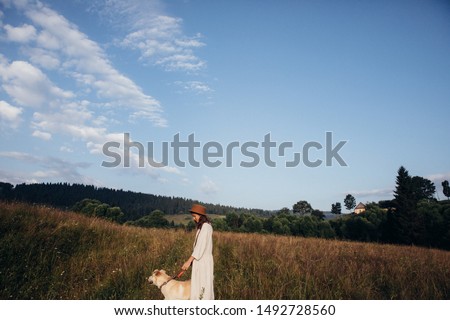 Beautiful young woman relaxed and carefree enjoying a summer sunset with her lovely dog on the straw field background
