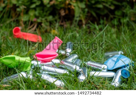 Nitrous oxide canisters / cream puff chargers and balloons: the metal cylinders contain nitrous oxide / laughing gas which is used for whipping cream, but also as a legal high. Royalty-Free Stock Photo #1492734482