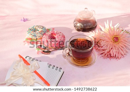 Flowers, donuts and a cup of tea on the desktop, top view, flat lay, copy space. A break at work in the office in comfortable conditions, the cosiness of our home, good morning