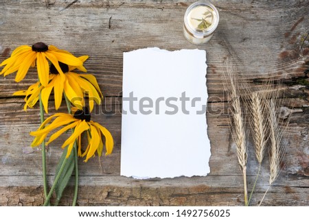 Blank greeting card. Vintage wood background. Flat lay, top view. Wedding invitation cards papers, yellow flowers, rye laying on table. Mockup.