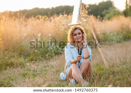 Pretty woman is painting. Open air session. Cute woman draws a picture at sunset. girl artist