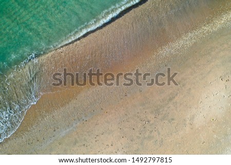 Drone photo of sand rock beach grass with blue water