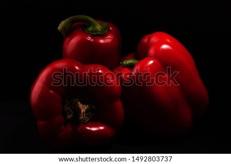 Three red sweet peppers on black background .closeup