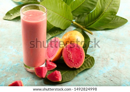 Healthy cold drinks- delicious organic pink guava milk shake juice glass on a rustic background