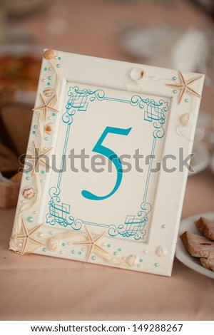 Wedding Table Decoration sea style decor at tropical royal wedding. Stylish wedding table numbers at bridal dinner. Wedding decoration with seashells. wedding picture frames decorated with starfish