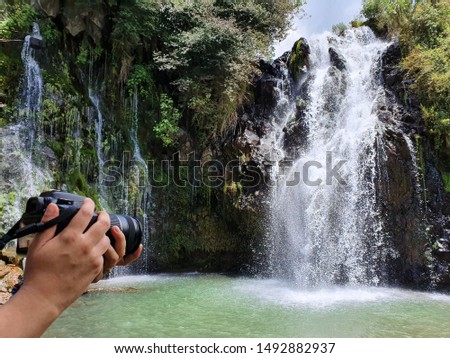 landscape and nature photography, hands with a camera near a waterfall
