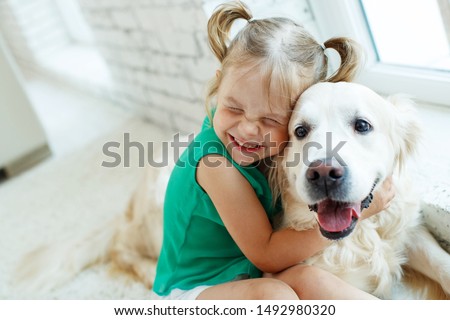 A child with a dog. Girl with a Labrador at home.  Royalty-Free Stock Photo #1492980320