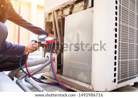 Technician is checking air conditioner ,measuring equipment for filling air conditioners. Royalty-Free Stock Photo #1492986716