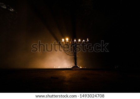 Low key image of jewish holiday Hanukkah background with menorah (traditional candelabra) on dark toned foggy background