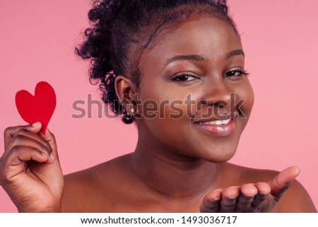 dark skin lady showing two paper card heart shape figure form lovely date invitation isolated pink studio background,sending airkiss.