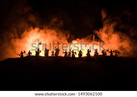 Medieval battle scene with cavalry and infantry. Silhouettes of figures as separate objects, fight between warriors on dark toned foggy background with medieval castle. Selective focus Royalty-Free Stock Photo #1493062100
